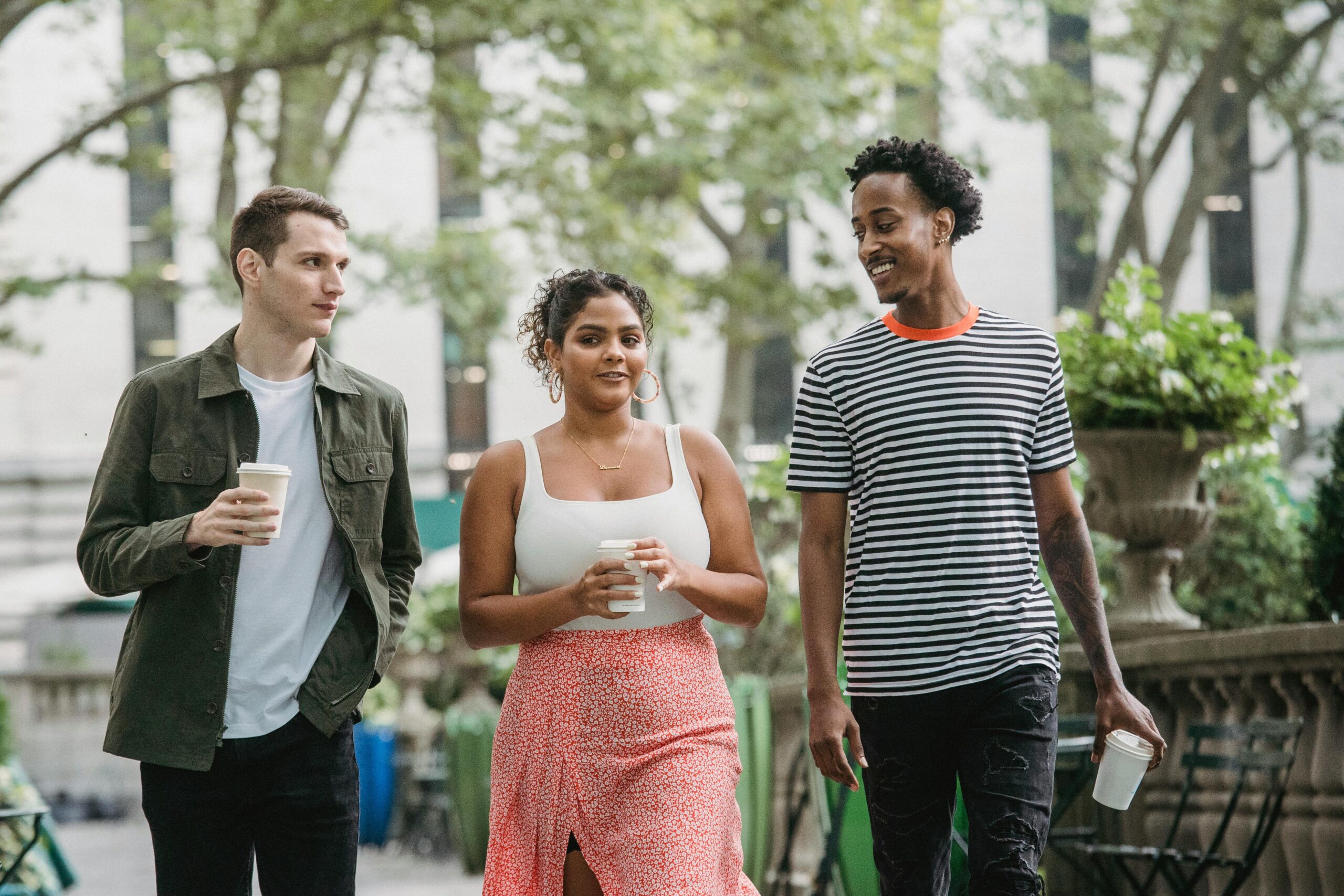 Group of young adults walking outside, carrying cup of coffee